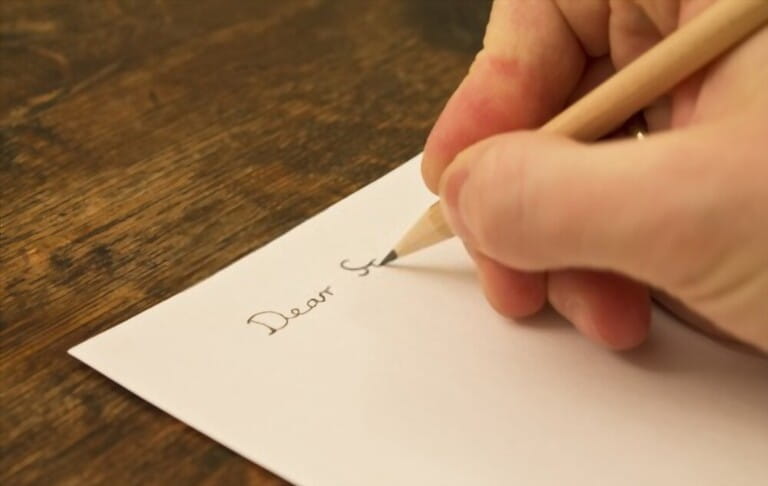 Close-up image of a hand holding a pen to write a letter Close-up image of a hand holding a pen to write a letter