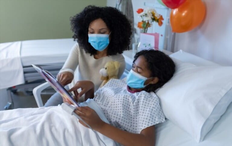mother reading book with her sick daughter in hospital 
