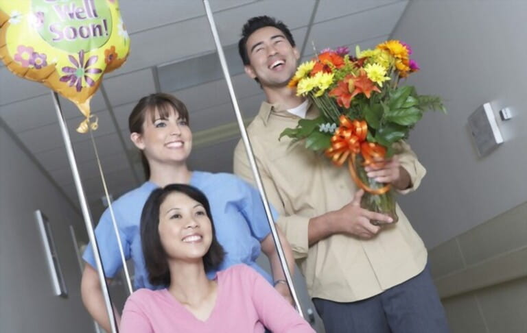 nurse assisting female patient on wheelchair with flowers and balloon of her friend nurse assisting female patient on wheelchair with flowers and balloon of her friend