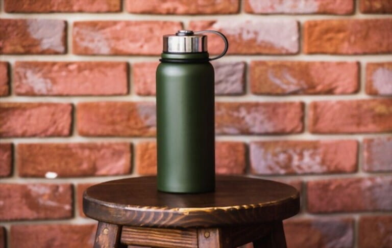 Thermos bottle near brick wall background. Coffee or tea reusable bottle container. Thermos travel tumbler. Insulated drink container. Thermos bottle near brick wall background. Coffee or tea reusable bottle container. Thermos travel tumbler. Insulated drink container.