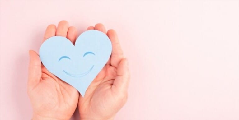 Holding a heart with a smiling face, colorful background with copy space, valintines day greeting card, love concept Holding a heart with a smiling face, colorful background with copy space, valintines day greeting card, love concept