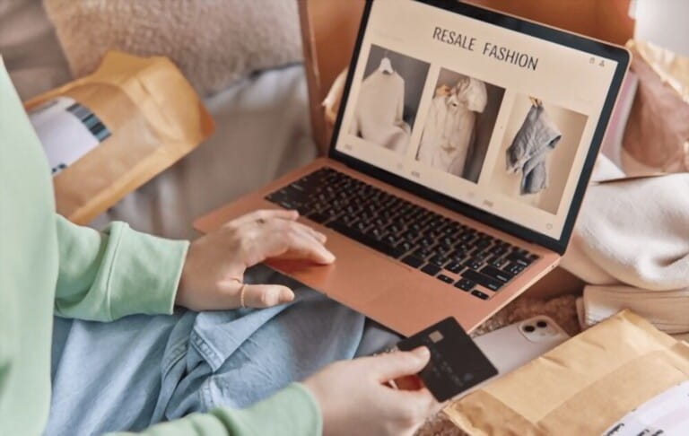 Unrecognizable person buys clothes on resale fashion makes shopping onine uses laptop uses laptop computer holds credit card consumes fashion sits crossed legs on bed. Cropped shot. Reselling concept Unrecognizable person buys clothes on resale fashion makes shopping onine uses laptop uses laptop computer holds credit card consumes fashion sits crossed legs on bed. Cropped shot. Reselling concept