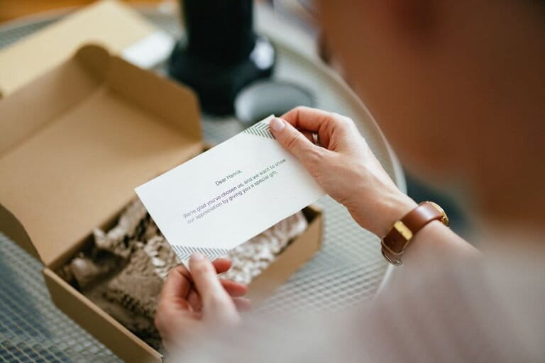 Chopped image of a woman reading a small note attached to an open gift box placed on the table Chopped image of a woman reading a small note attached to an open gift box placed on the table