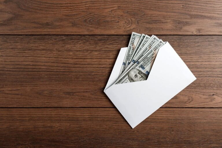 US dollars in a white envelope on wooden table. The concept of income, bonus US dollars in a white envelope on wooden table. The concept of income, bonus