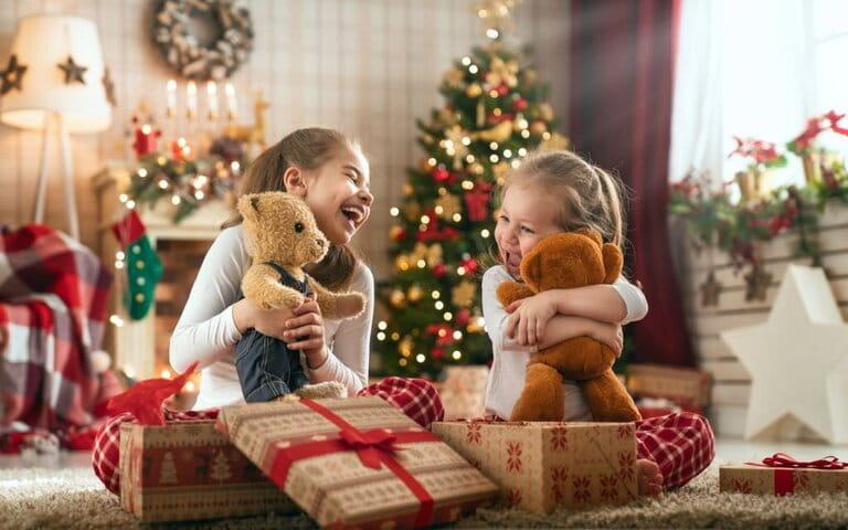 Two little girls are excitedly opening meaningful gifts for Christmas