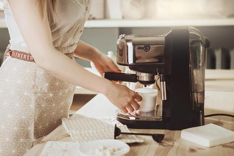 Woman making fresh espresso in coffee maker. Coffee maker makes coffee. Barista Coffee Maker Grinder Portafilter Concept