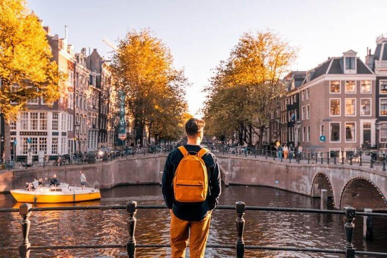 Rear view of a man looking at Amsterdam canal on a sunny day, Netherlands 