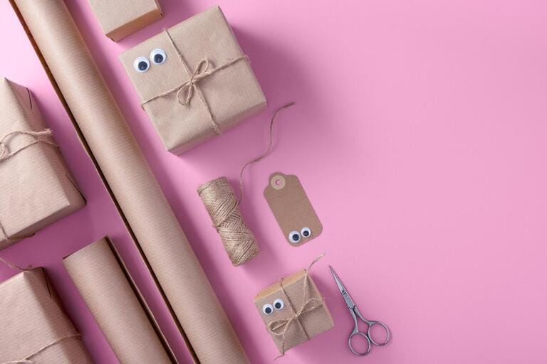 Banner with packaging materials on pink background. Gift box, wrapping paper, gift tags, jute, scissors.