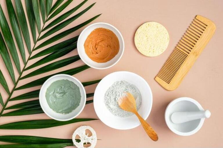 Natural SPA cosmetics for skincare, body and hair care. Top view facial clay masks, loofah, sponge, hair comb on peach background Natural SPA cosmetics for skincare, body and hair care. Top view facial clay masks, loofah, sponge, hair comb on peach background