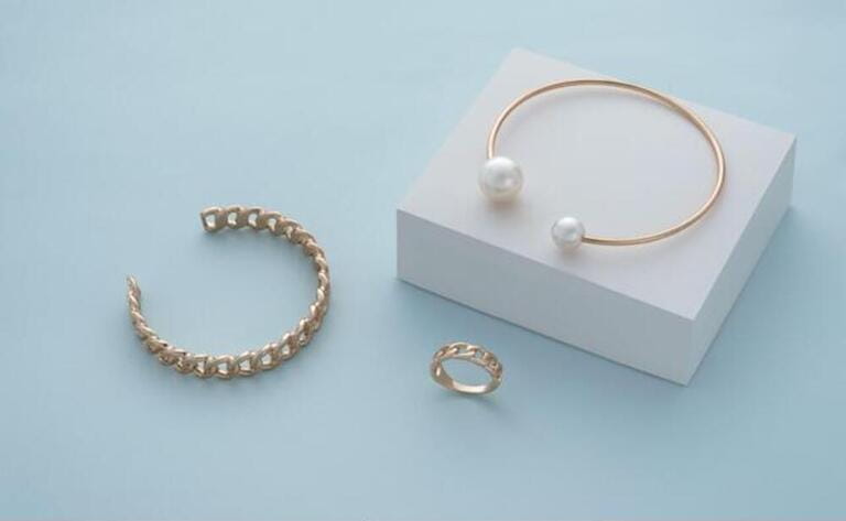 Golden pearl bracelet on white box and golden chain shape bracelet and ring on blue background Captions are provided by our contributors. Golden pearl bracelet on white box and golden chain shape bracelet and ring on blue background Captions are provided by our contributors.