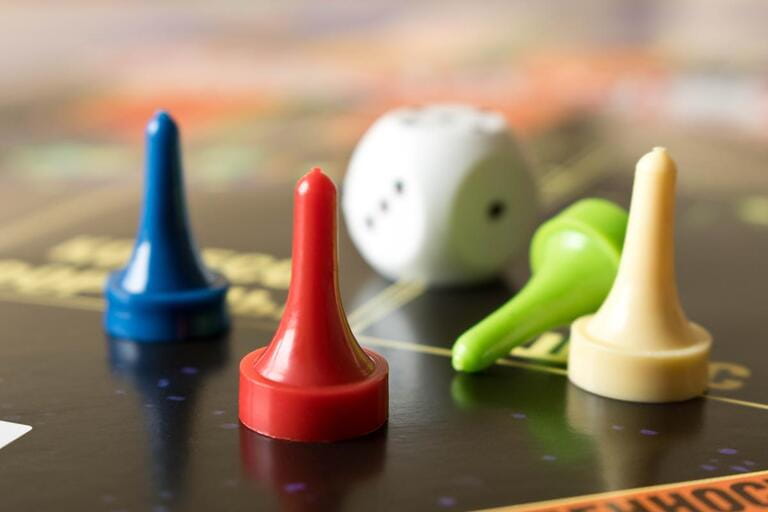 Multi-colored game chips with dice on the playing board. Board game.