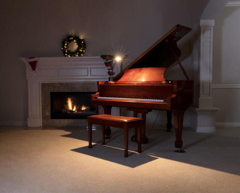 Piano with reading light and glowing fireplace during holiday season Piano with reading light and glowing fireplace during holiday season