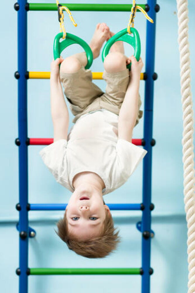 Kid boy on the gymnastic rings in the gym class Kid boy on the gymnastic rings in the gym class