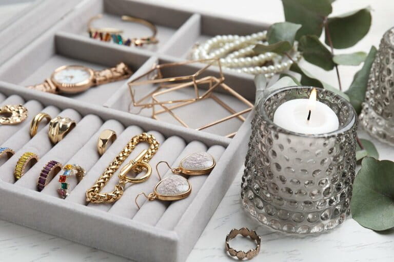 Elegant jewelry box with beautiful bijouterie and burning candles on white wooden table, close-up Elegant jewelry box with beautiful bijouterie and burning candles on white wooden table, close-up