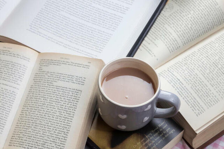 Mug of tea on tabletop covered with books Mug of tea on tabletop covered with books