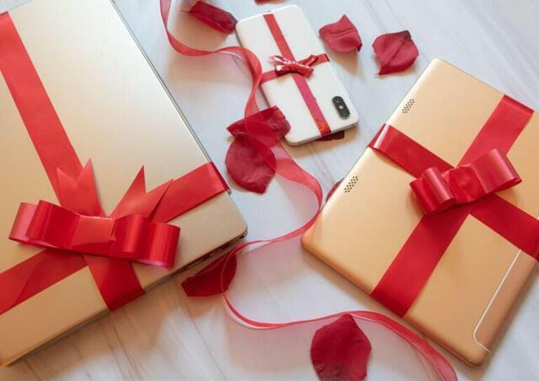 Tech gifts wrapped with red gift bows, tablet, cell phone, laptop, smart speaker Tech gifts wrapped with red gift bows, tablet, cell phone, laptop, smart speaker
