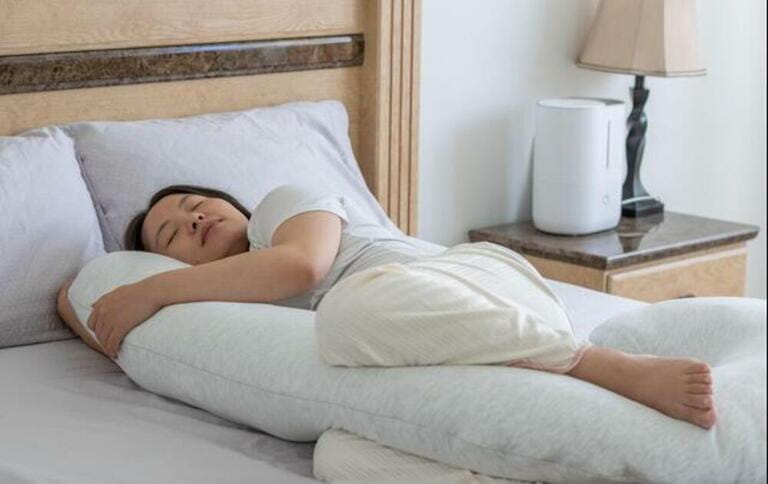 Close up view of a pregnant woman sleeping on the bed with the pregnancy pillow Close up view of a pregnant woman sleeping on the bed with the pregnancy pillow