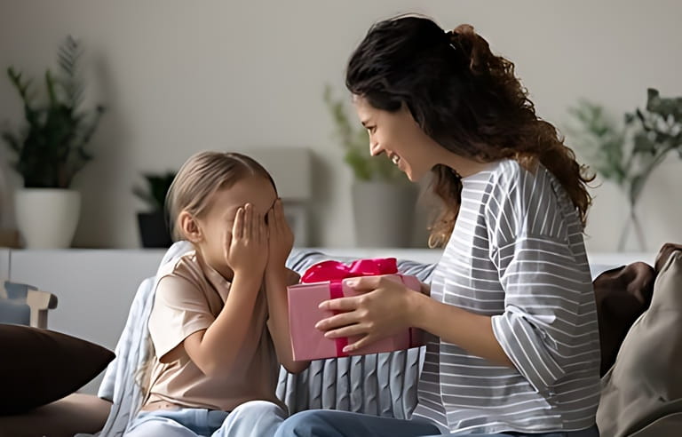 Loving young Hispanic mother congratulate excited small daughter with birthday give wrapped gift. Caring happy Latin mom greeting make surprise with present for little girl child, celebrate together.